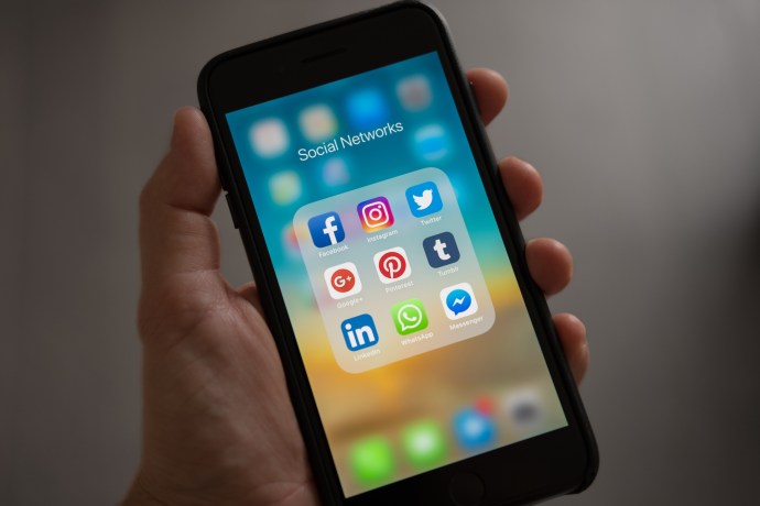 Orang yang Memegang Iphone Menampilkan Folder Jejaring Sosial